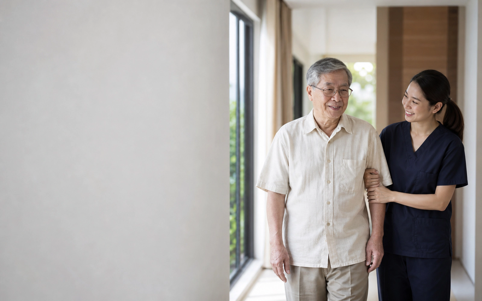 An older man walking at home with a caregiver supporting him